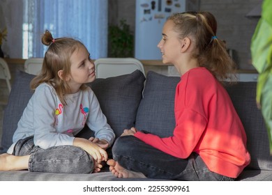 A teenage girl and her sister look at each other and talk while sitting at home. The concept of trusting relationships and help in solving the problem, understanding and friendship - Shutterstock ID 2255309961