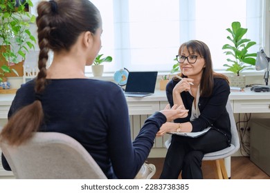 Teenage girl high school student talking with mentor, psychologist in office - Powered by Shutterstock