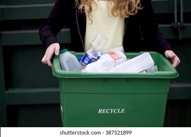 A Teenage Girl Holding A Recycling Container