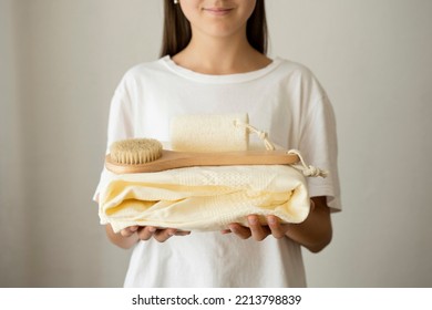 A Teenage Girl Is Holding A Towel With A Wooden Body Brush And A Loofah.