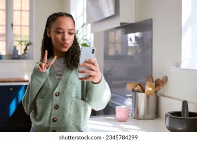 Teenage Girl At Home In Kitchen Posing For Selfie To Upload To Social Media On Mobile Phone - Powered by Shutterstock