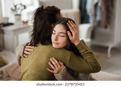 Teenage girl hugging her mother at home.