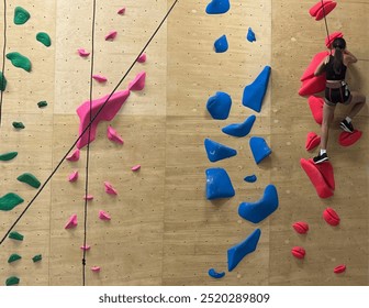 Teenage girl at indoor climbing wall. Kid having fun at bouldering wall. Child learning at climbing class. Sports healthy lifestyle. Youth at climbing summer camp - Powered by Shutterstock