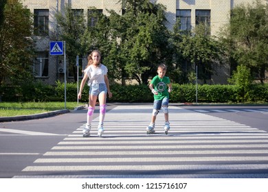 Teenage girl in jeans short rollerskating with brother and cross the road at a pedestrian crossing. Kiev, Ukraine - 30.08.2018 - Shutterstock ID 1215716107