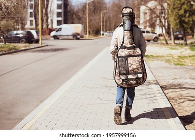 A Teenage Girl With A Large Guitar Bag Goes To A Private Guitar Lesson, Rear View. The Girl Loves To Play The Guitar And Often Studies At Home And Studies At A Private Music School