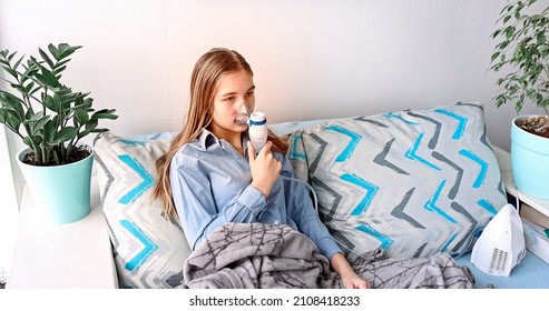 Teenage Girl Makes Inhalation With A Nebulizer Equipment. Sick Child Holding Inhalator In Hand And Breathes Through An Inhaler At Home. Physical Therapy For Cold, Flu And Broncial Asthma