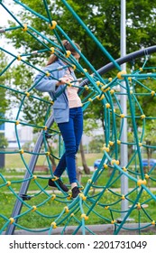 A Teenage Girl Of Middle School Age In A Rope Park. Joy And Fun. Hobby. Recreation Area In The City. Healthy Active Pastime. Games, Adventures In The Park Alone. Rock Climbing, Outdoor Activity, Sport