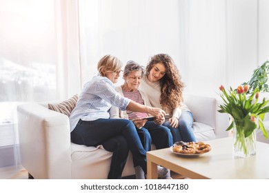 A teenage girl, mother and grandmother with tablet at home.