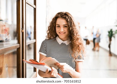 Teenage Girl With Notebooks In High School Hall During Break.