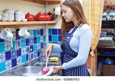 Teenage Girl With Part Time Job Washing Up In Coffee Shop