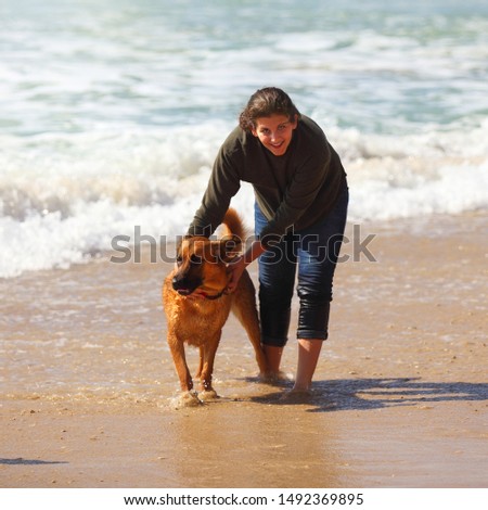 Teenage girl  playing with her dog on the beach