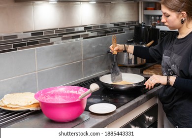 A Teenage Girl Pricks Up A Partially Baked Pancake With The Kitchen Spatula And Prepares To Turn It Over. Homemade Pancakes.