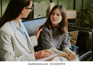 Teenage girl with prosthetic limb engaging with therapist on sofa focusing on recovery and future steps Together discussing personal progress in friendly environment - Powered by Shutterstock