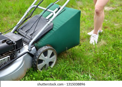 Teenage girl pruning green high grass with the help of an petrol lawn mower. - Shutterstock ID 1315038896