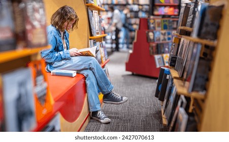 Teenage girl reading the book in large bookshop of London - Powered by Shutterstock