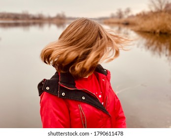 A Teenage Girl In Red Winter Coat Whipping Hair By River