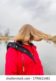 A Teenage Girl In Red Winter Coat Whipping Hair By River