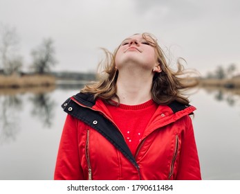 A Teenage Girl In Red Winter Coat Whipping Hair By River