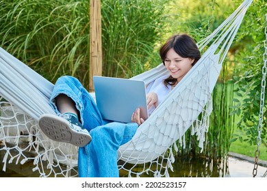 Teenage Girl Relaxing In Hammock Using Laptop For Leisure Study