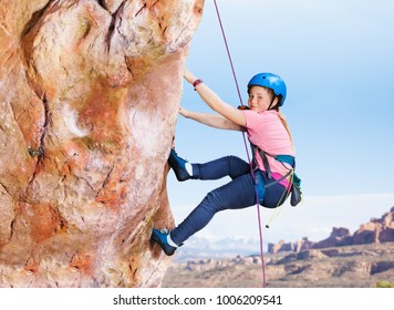 Teenage girl rock climbing high in the mountains