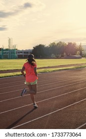 Teenage Girl Running Backwards On The Track Towards Sunset