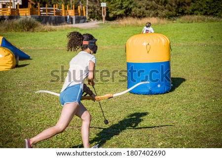 teenage girl running with bow and arrow during a game of archery tag