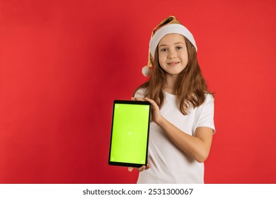 Teenage girl in santa hat on red background holding laptop with green screen, copy space, chroma key. - Powered by Shutterstock