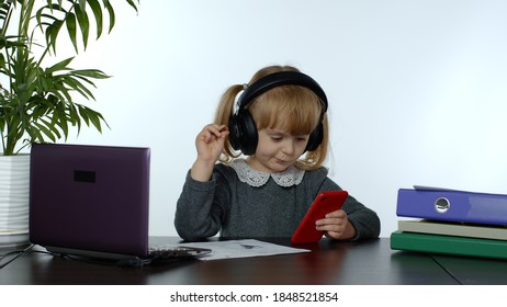 Teenage Girl School Student Wearing Wireless Headphones Calling To Teacher On Mobile Phone. Distance Education Learning At Home. Teen Schoolgirl Chatting By Web Cam Preparing For Test, Exam. Homework