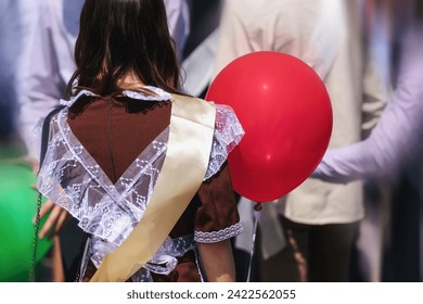 A teenage girl in school uniform with a red balloon in her hand.. Parade of schoolchildren, graduates with bright balloons colorful in hands. - Powered by Shutterstock