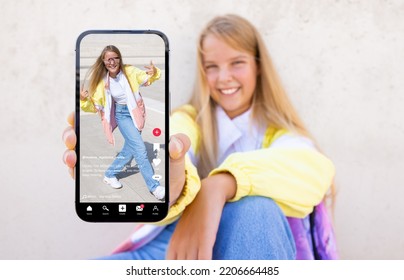 Teenage girl showing mobile phone with sample video content shared on social media  - Shutterstock ID 2206664485