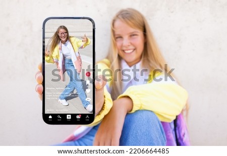 Teenage girl showing mobile phone with sample video content shared on social media 