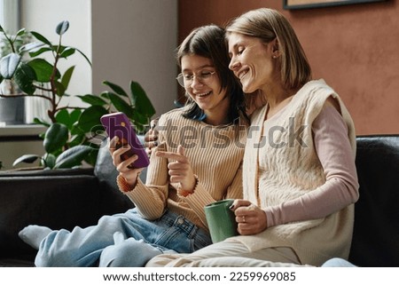 Teenage girl showing photos to her mom