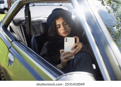 teenage girl sitting inside a car looking at her cell phone - Powered by Shutterstock