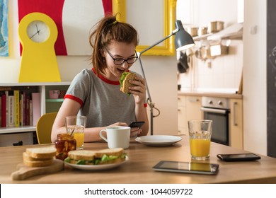 Teenage Girl Sitting Table And Eating Sandwich At Her Home