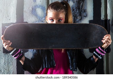 Teenage girl with skateboard, on the street at night - Powered by Shutterstock