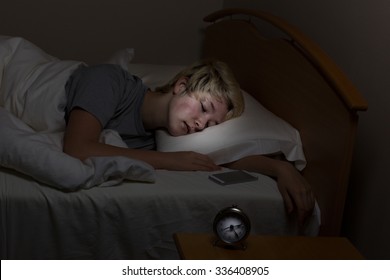 Teenage Girl Sleeping Bed With Her Cell Phone On Night Stand. Teen Surrounded By Technology Even Late At Night. 