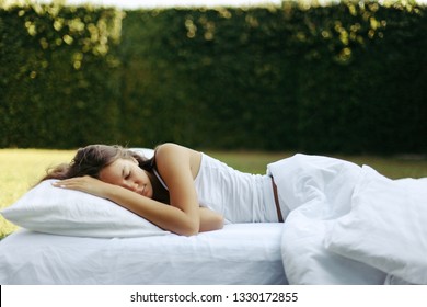 Teenage Girl Sleeping On Soft Mattress And Pillow On Grass Outside. Healthy Relaxing On Cosy Bed On Fresh Air In Garden.