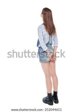 Teenage girl standing and looking on something isolated. Back pose, full length