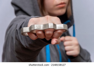 A Teenage Girl Strikes With Brass Knuckles On A Light Background.