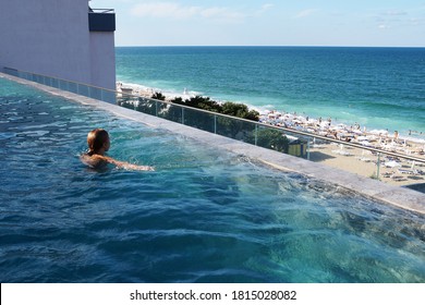 Teenage Girl Swimming In The Rooftop Pool With Sea View.