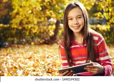 Teenage Girl With Tablet Computer In Autumn Park Outdoor