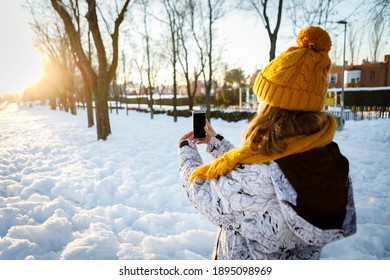 Teenage Girl Taking Pictures In The Snow With A Smart Phone