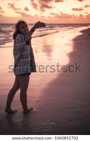 Teenage girl taking selfie photo on the beach in early morning