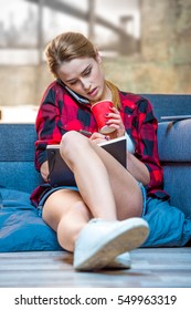 Teenage Girl Talking On Smartphone Making Notes In Notebook And Drinking Tea