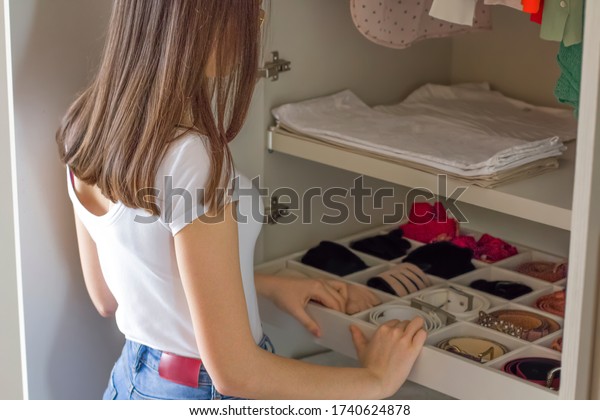 Teenage\
girl tidying up the wardrobe at home. Everything is folded neatly.\
Everything is in its place. Concept of tidy Interior and\
collaboration of young people in the\
housework