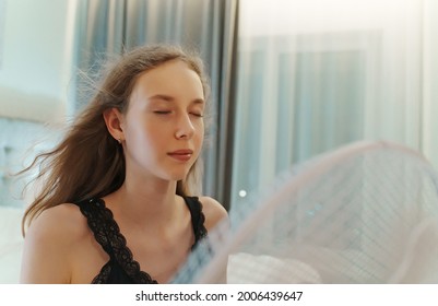 Teenage Girl Tries To Cool Off During The Intense Heat In Front Of Cooling Fan.