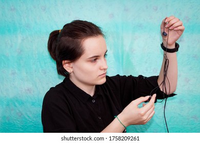 A Teenage Girl Tries To Untangle The Wires From Her Headphones. Close Up.