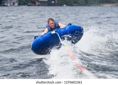 A Teenage Girl Tubing Behind A Boat On A Lake