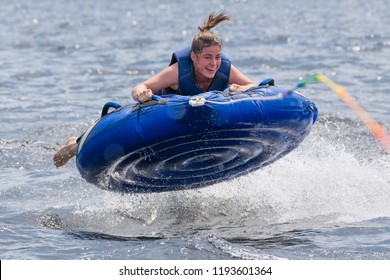 A Teenage Girl Tubing Behind A Boat On A Lake