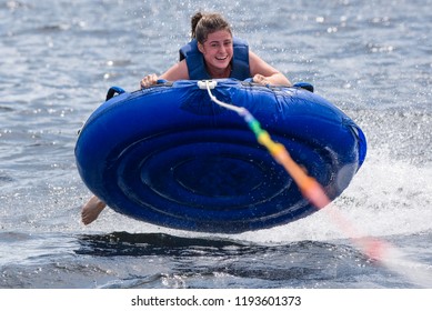 A Teenage Girl Tubing Behind A Boat On A Lake